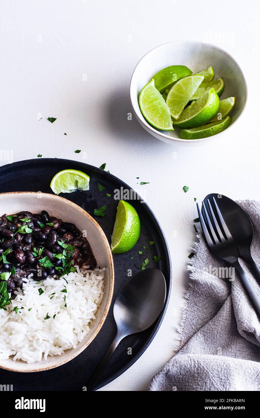 Schüssel mit schwarzen kubanischen Bohnen serviert mit Reis und Kalk-Keile. Stockfoto