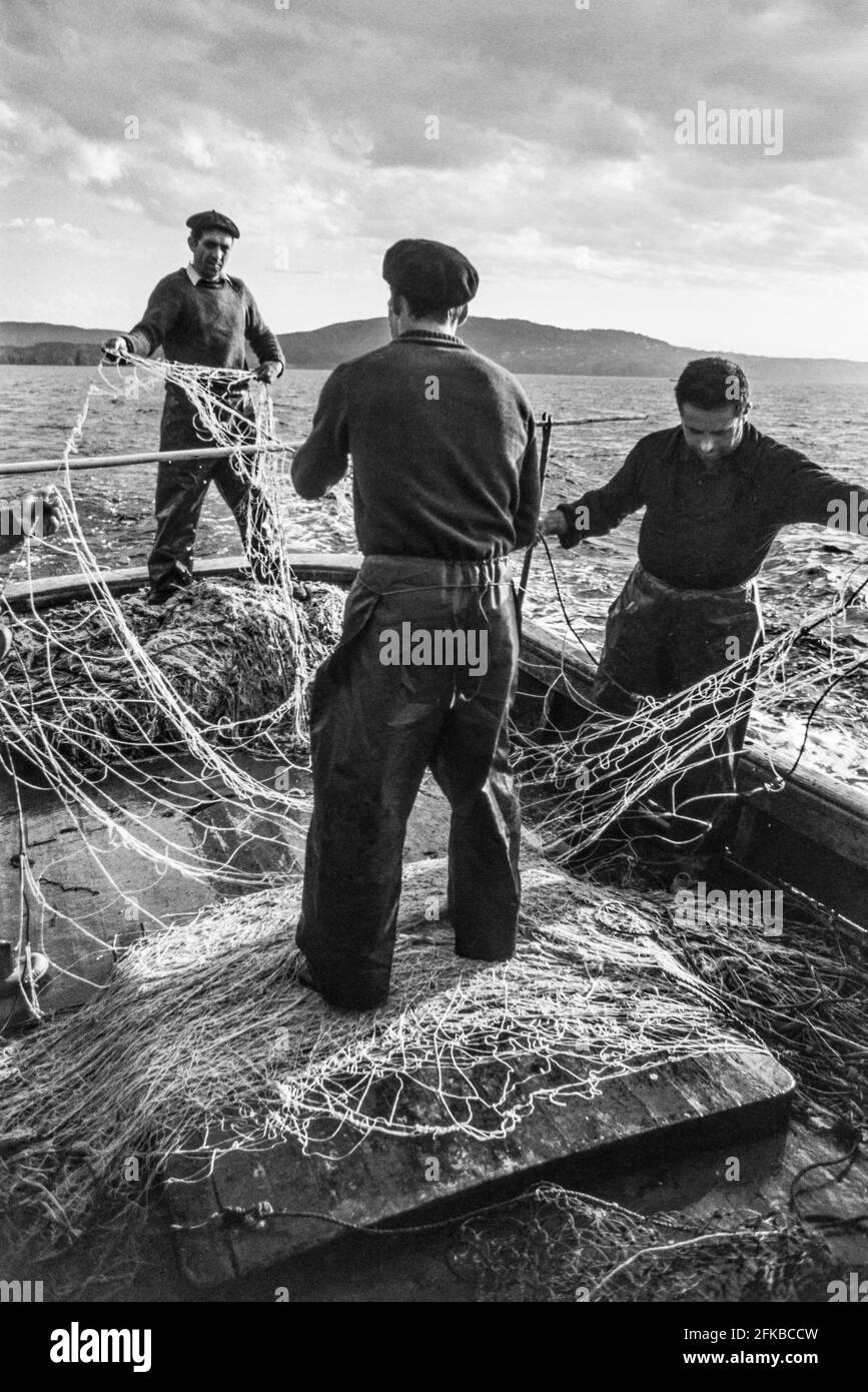 SPANIEN - Galicien - 1970. Spanische Fischer, die ihre Netze sortieren, vor der Küste VON A Coruña, Galizien, Nordwestspanien. Foto Copyright: Peter Eastland. Stockfoto