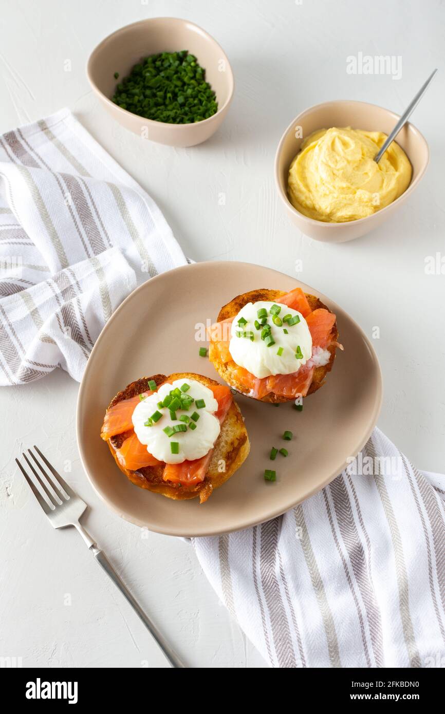 Leckeres herzhaftes Frühstück, Eier Atlantic in einem Teller auf weißem Hintergrund, Runde gebratene Brötchen mit Lachs und Eier Benedikt, Sauce Hollandaise Stockfoto
