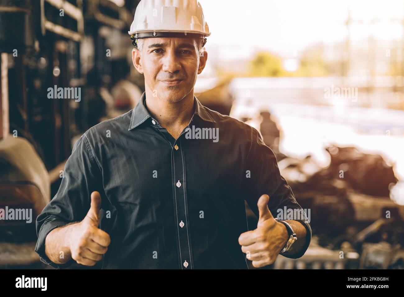 Professionelle Erwachsene Ingenieur männliche Arbeit in der Fabrik stehende Hände zeigen Zwei Daumen nach oben für gute Arbeit oder beste Arbeit mit Selbstbewusstes Lächeln Stockfoto