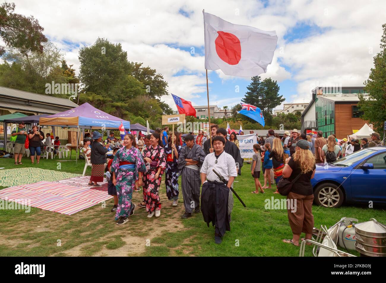Japaner, einige tragen traditionelle Kimonos und marschieren mit der japanischen Flagge auf einem multikulturellen Fest. Tauranga, Neuseeland Stockfoto
