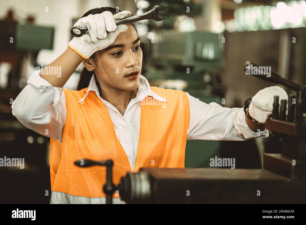 Müde Frau Arbeiter Asian Arbeit harte Arbeit in heißen Fabrik wegwischen Schweiß arbeiten mit Metall-Maschine. Stockfoto