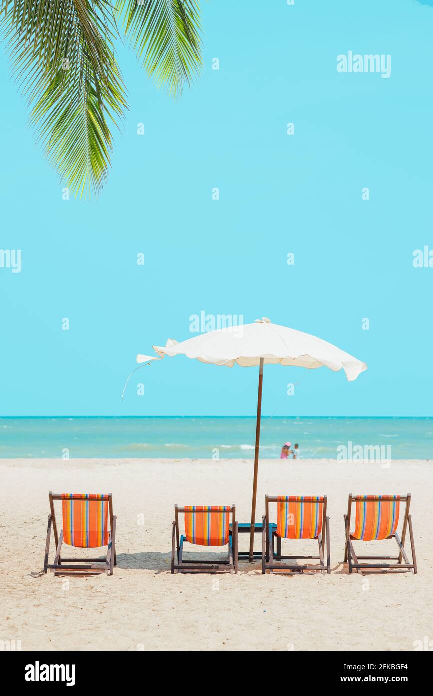 Sommer Meer Strand leeren Stuhl Sonnenschirm mit blauen Ozeanhimmel Für Reise Natur Hintergrund vertikale Aufnahme Stockfoto