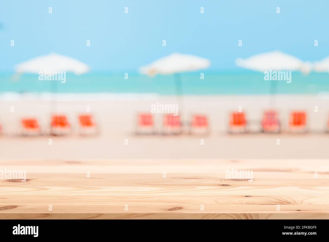 Sommer Liegestuhl Sonnenschirm verschwimmen mit Holztischplatte für Montage Produkte Hintergrund Werbefläche Stockfoto