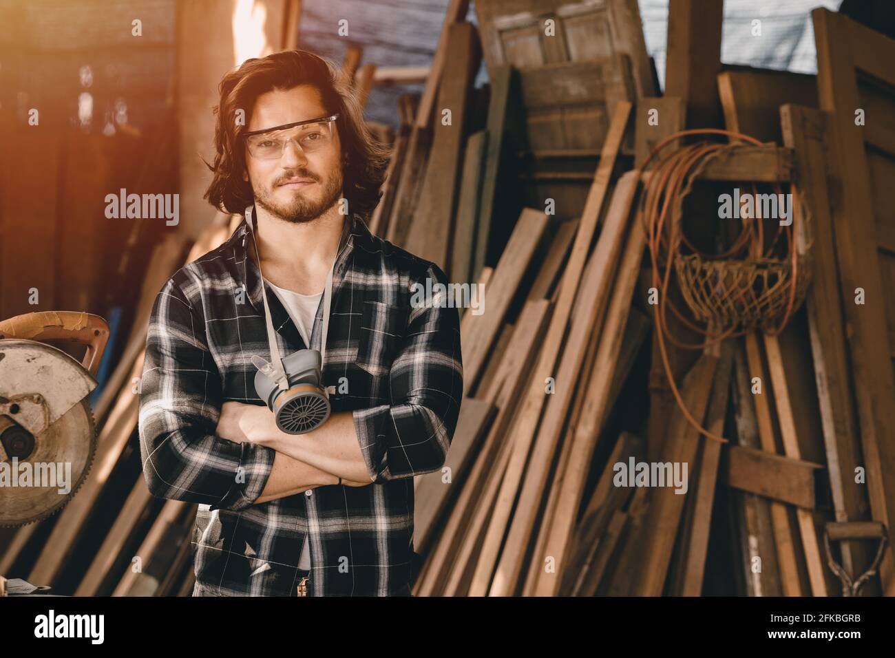 Junge Tischler Mann neue Generation Geschäft Holzarbeiter Herstellung von Möbeln. Porträt eines männlichen stehenden Armes aus Holz, gekreuzt in der Holzwerkstatt. Stockfoto