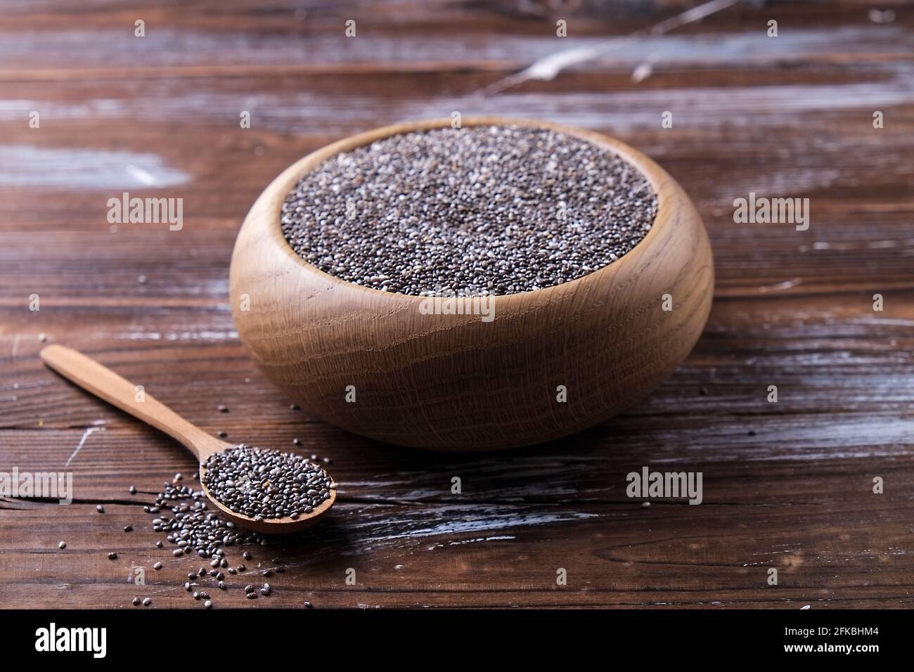 Draufsicht auf Holzschüssel mit Stapel von Bio-schwarzen Chia-Samen und Löffel auf geronged Holz strukturierte Tisch. Gesunde nahrhafte vegane Ernährung suppliment. Clea Stockfoto