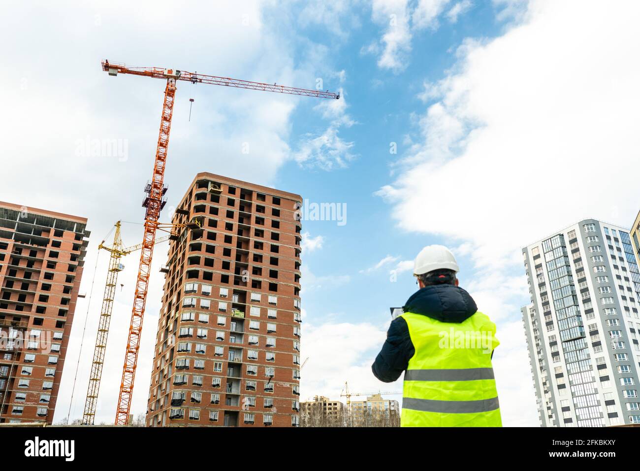 Beratender Ingenieur auf der Baustelle, der den Bauplan in der Hand hält. Bauinspektor. Baustelleninspektion Zeichnung und neue Bauarbeiten Stockfoto