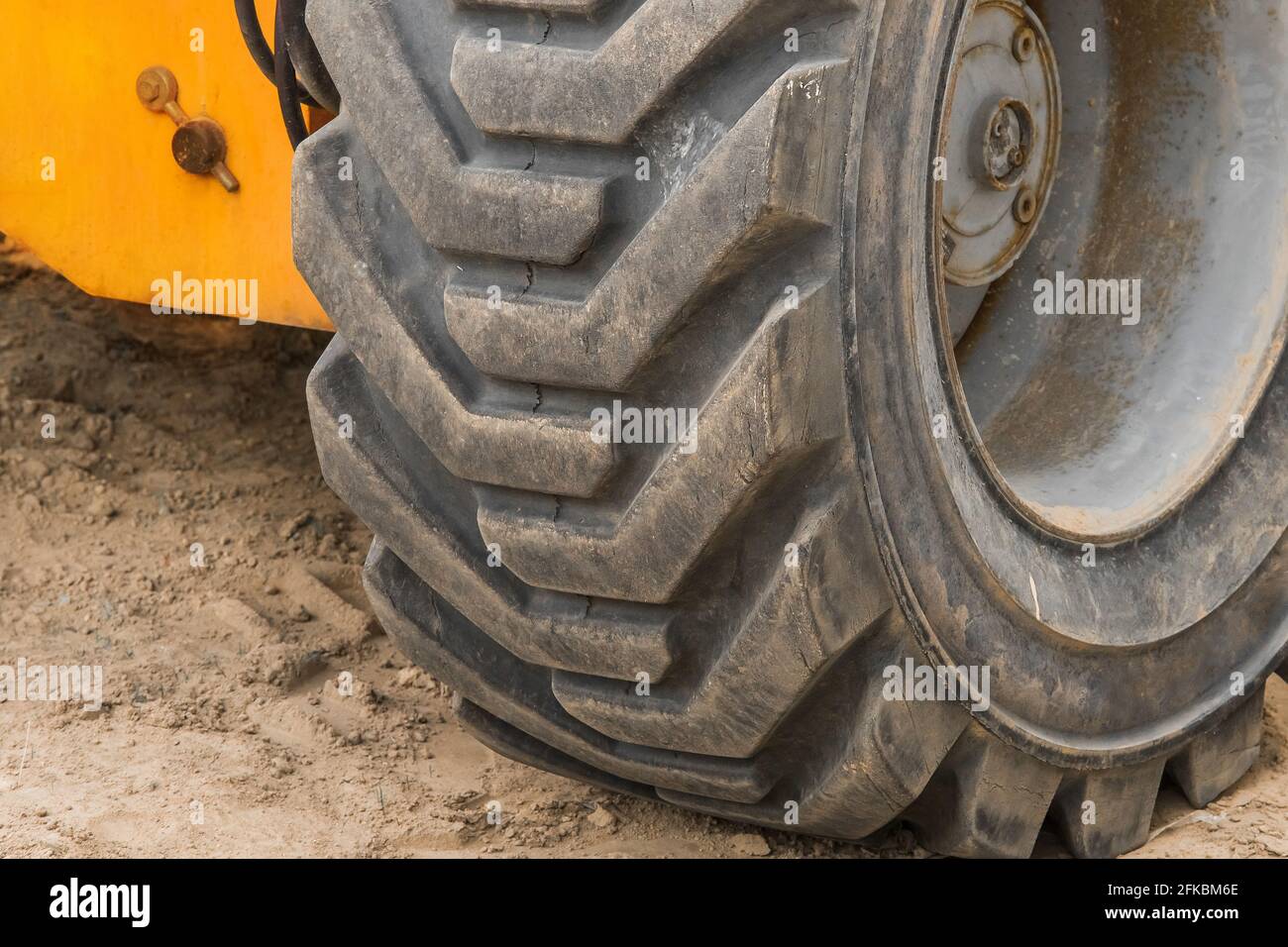 Räder von industriellen Hubwagen transportieren Reifen vor dem Hintergrund von Sand auf einer Baustelle. Stockfoto