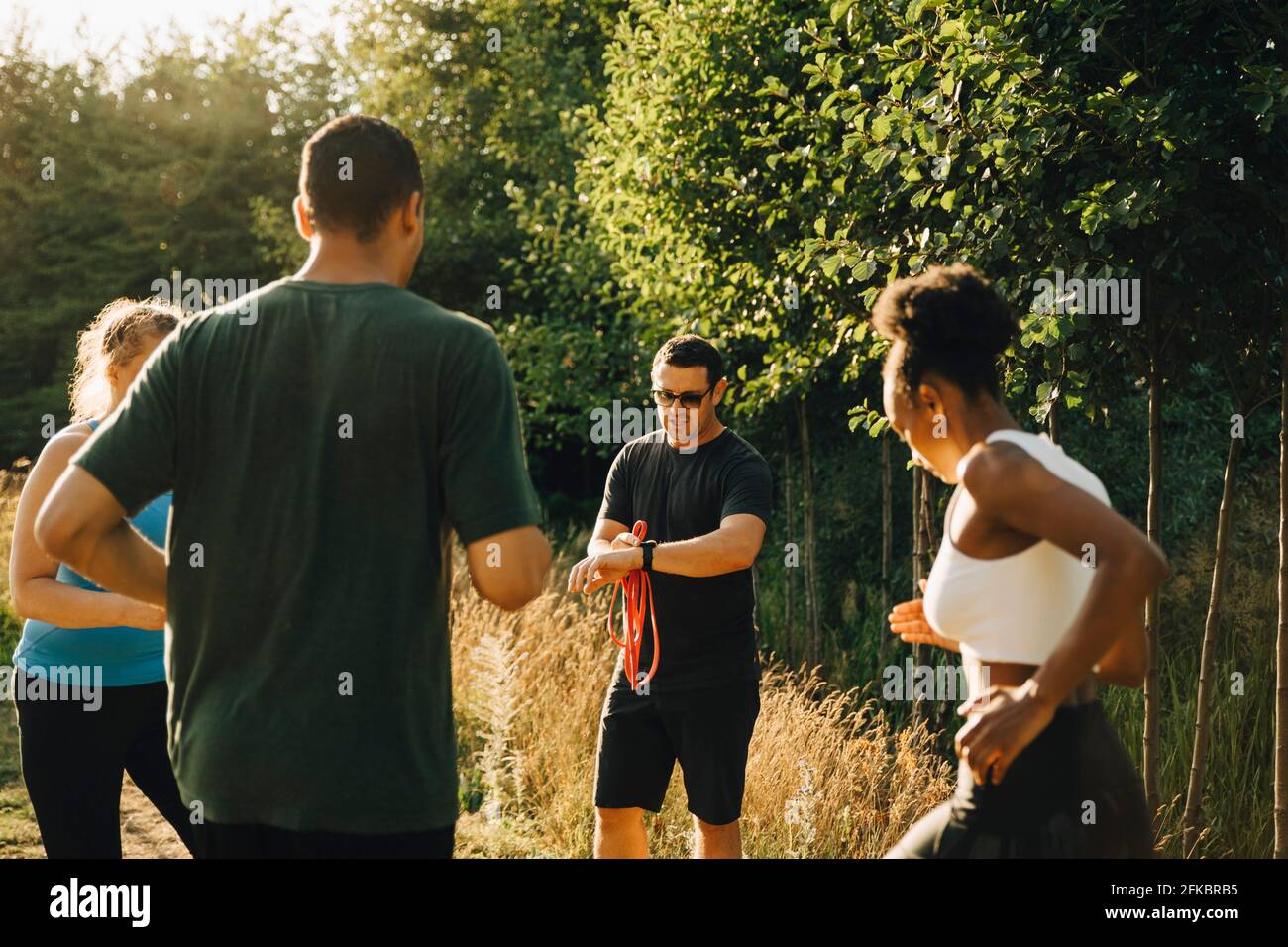 Fitnesstrainer trainiert männliche und weibliche Athleten beim Training in parken Stockfoto