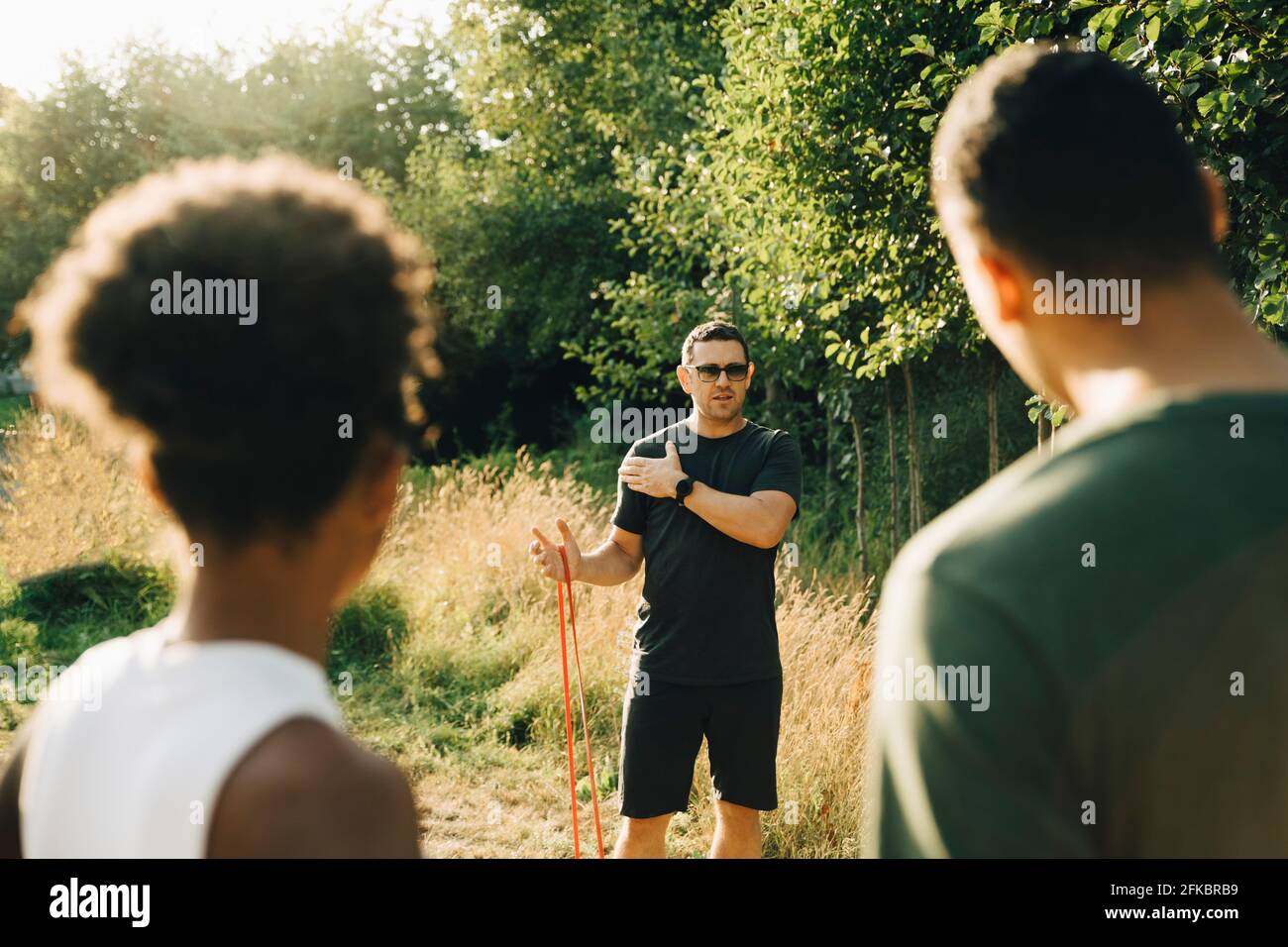 Fitnesstrainerin trainiert im Park On männliche und weibliche Athleten Sonniger Tag Stockfoto