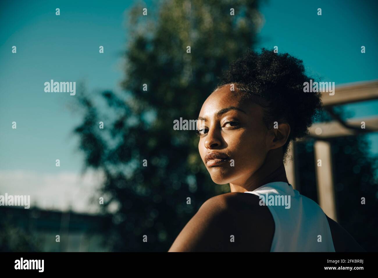 Porträt einer Sportlerin, die an einem sonnigen Tag über die Schulter schaut Stockfoto