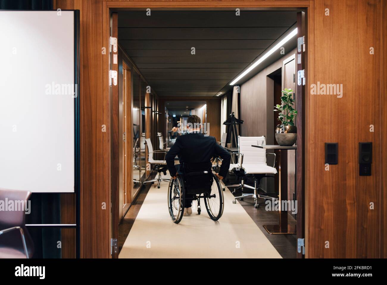Rückansicht eines behinderten Geschäftsmanns im Rollstuhl im Büro Stockfoto