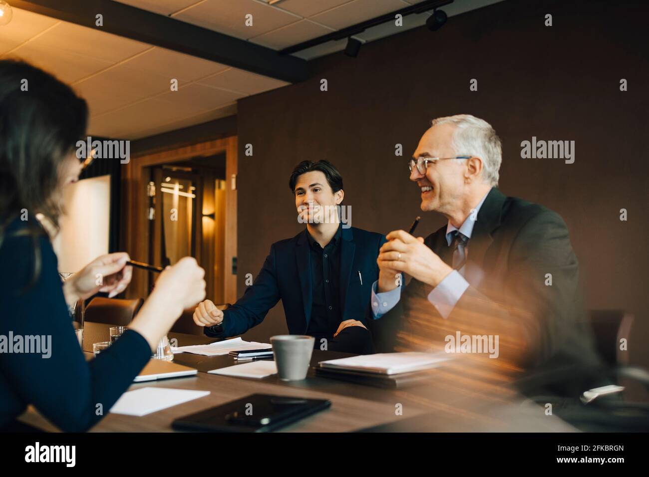 Lächelnder Geschäftsmann, der mit einem Kollegen an Bord diskutiert Zimmer Stockfoto