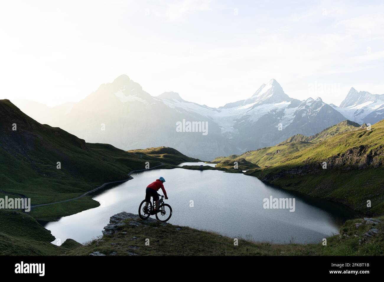 Mountainbiker, die im Morgengrauen am Bachalpsee bergab fahren, Grindelwald, Berner Oberland, Kanton Bern, Schweiz, Europa Stockfoto