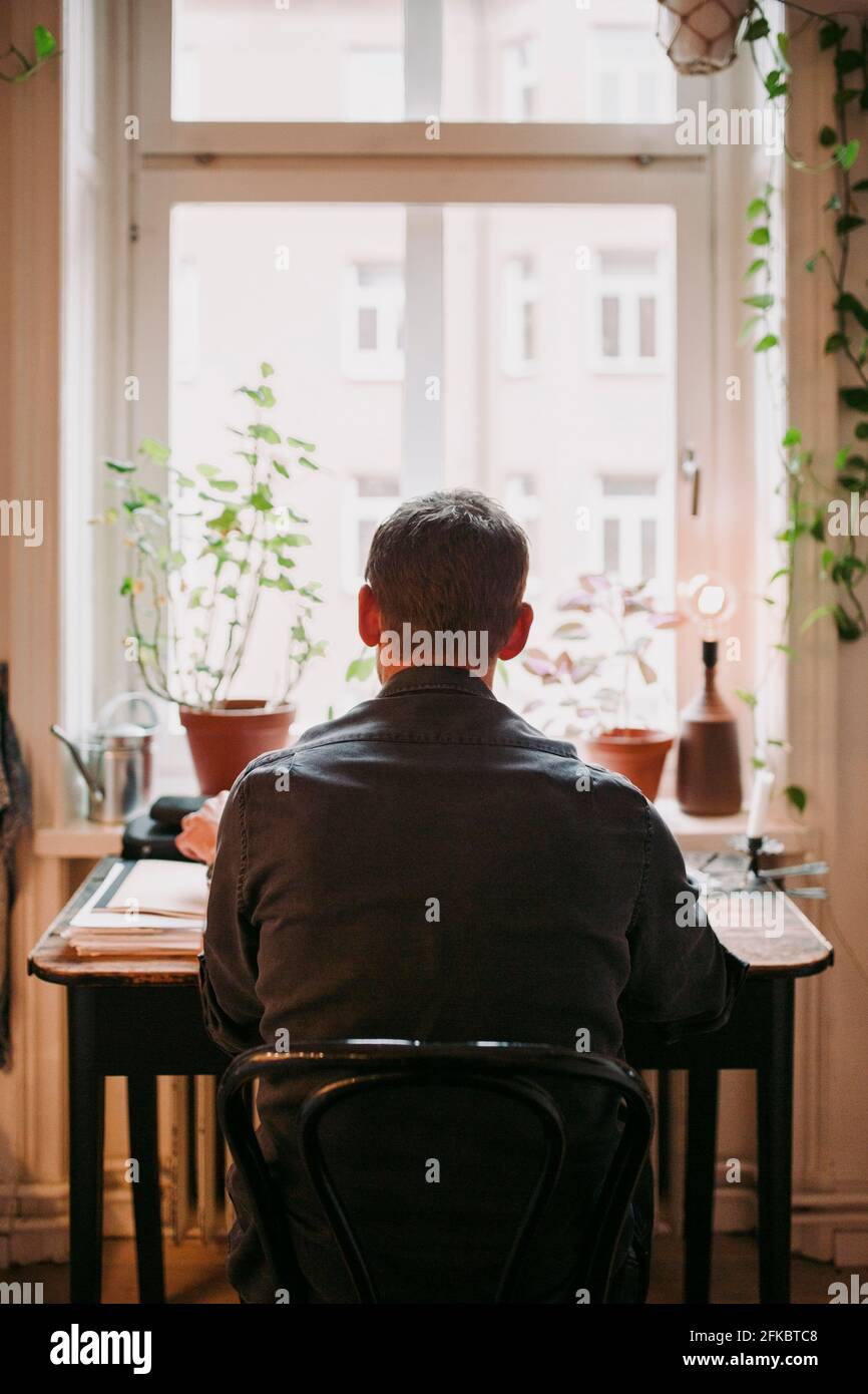 Rückansicht eines Geschäftsmanns, der im Heimbüro auf einem Stuhl sitzt Stockfoto