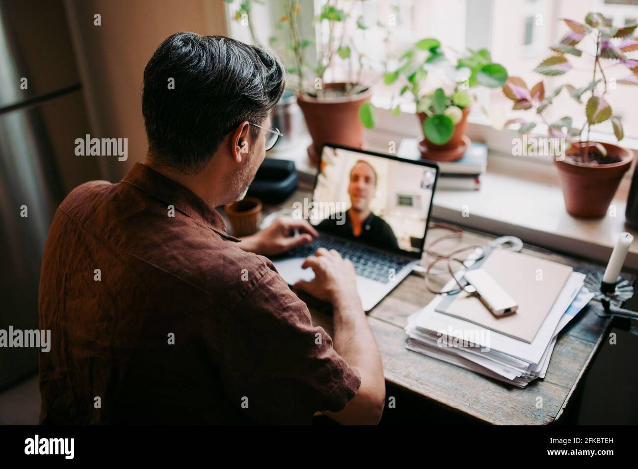 Männlicher Unternehmer, der zu Hause mit einem Kollegen über Videoanruf spricht Büro Stockfoto