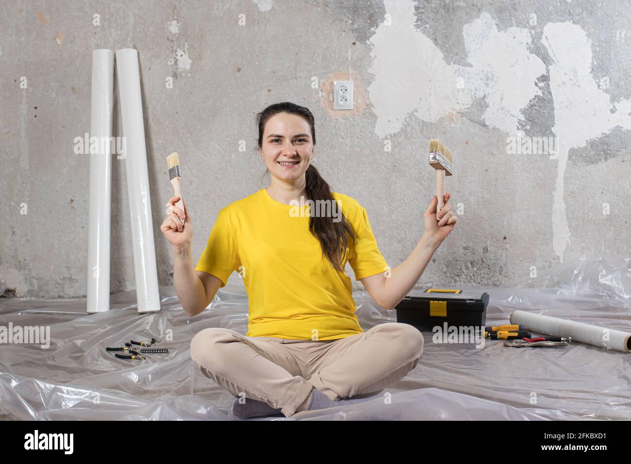 Eine Baumeisterin repariert das Haus. Reparieren von Schlüssel, Kitt und Tapete Stockfoto