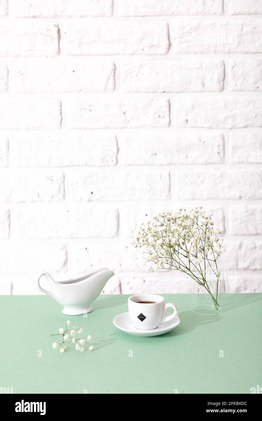 Gemütliches Frühlingsstill-Leben. Mockup-Szene für Grußkarten. Tasse Kaffee, Milchkrug und Blumenvase auf Fensterbank. Florale Komposition Stockfoto