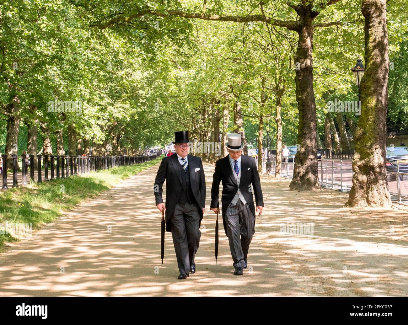 Männer in Frack und Zylinder schlendern Constitution Hill neben Green Park, London, UK Stockfoto