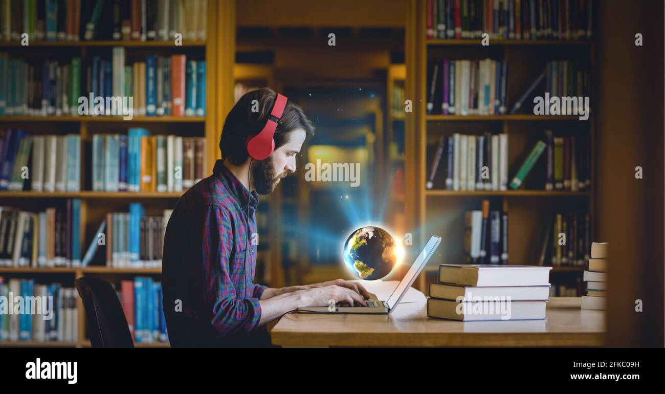 Komposition eines leuchtenden Globus über dem Mann, der Kopfhörer in der Bibliothek trägt Mit einem Laptop Stockfoto