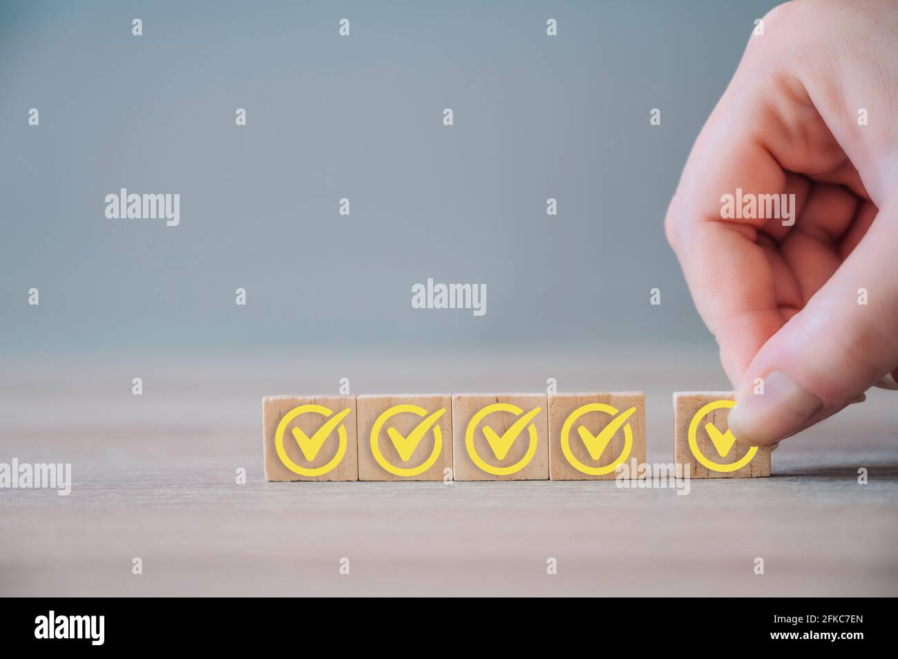 Checkliste Konzept, gelbes Häkchen auf Holzblöcken auf Holzhintergrund mit Kopierfläche. Holzblöcke mit Häkchen von Hand halten. Stockfoto