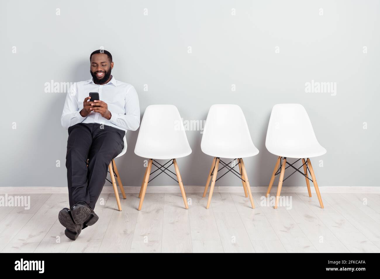 In voller Länge Körpergröße Foto von lächelnden Mann wartet auf Interview mit Smartphone tragen weißes Hemd formelle Kleidung Stockfoto