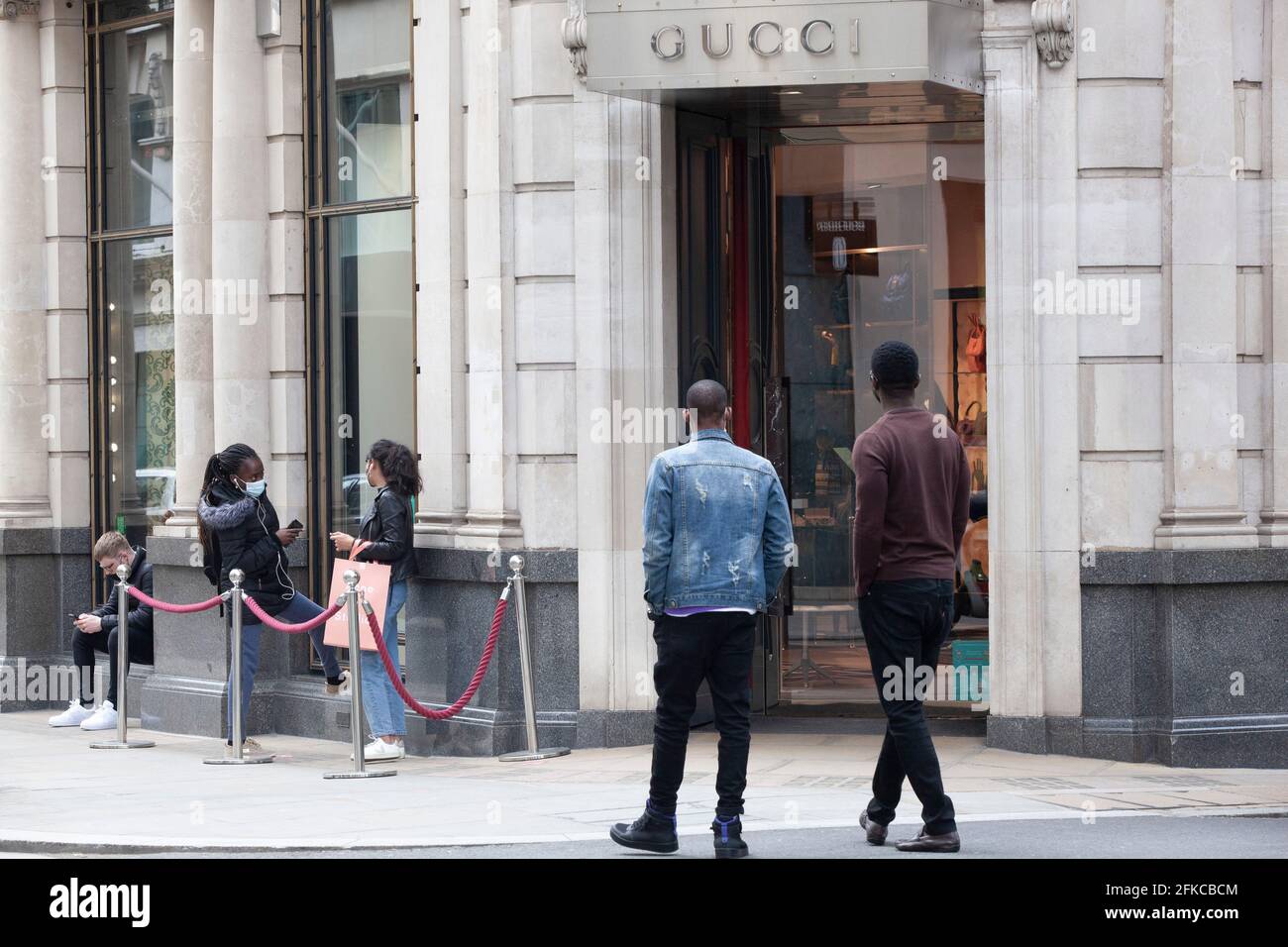 London, Großbritannien, 30. April 2021: Selbst an einem Freitagmorgen ziehen die Luxusboutiquen der Bond Street treue Kunden an, die bereit sind, sich für ein sozial distanziertes Einkaufserlebnis anzustellen und mit einigen Käufen von Designermarken nach Hause zu gehen. Anna Watson/Alamy Live News Stockfoto