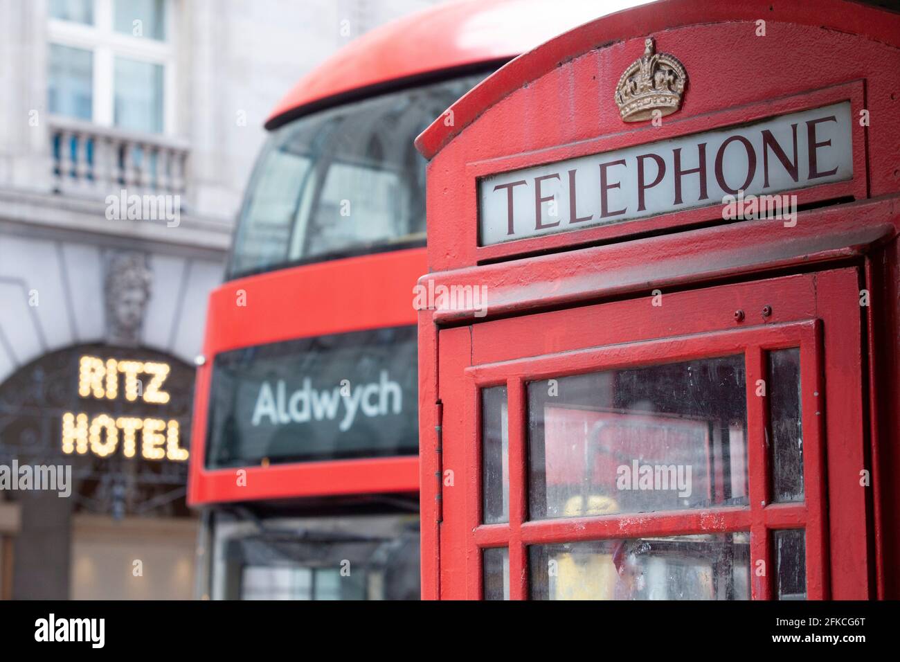 Eine britische rote Telefonbox gegenüber dem Ritz Hotel am Londoner Piccadilly, an der ein roter Londoner Bus vorbeifährt. Stockfoto