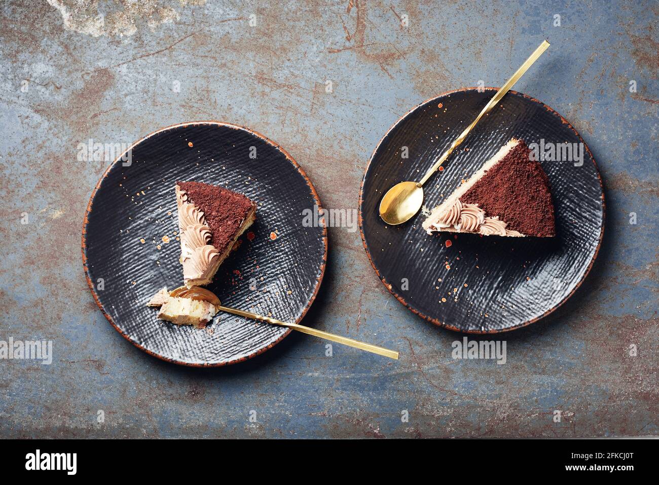 Zwei Stück Schokoladenkuchen auf schwarzen Tellern, Draufsicht. Stockfoto