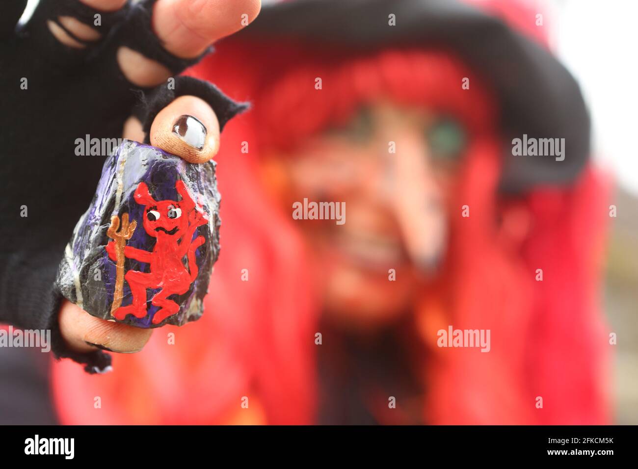 Schierke, Deutschland. April 2021. Ein Harzstein mit Teufelsmotiv zeigt Irmgard Eggert aus Halberstadt als Hexe verkleidet. Die handbemalten Steine sind angelegt und können von Wanderern gefunden und wieder versteckt werden. Ein beliebtes Spiel, das viele Anhänger in sozialen Netzwerken hat. Zum zweiten Mal in Folge werden die Walpurgisfeiern im Harz aufgrund der Corona-Pandemie abgesagt. In der Regel werden Zehntausende von Besuchern im Harz auf Walpurgis erwartet. (To dpa: >) Quelle: Matthias Bein/dpa-Zentralbild/dpa/Alamy Live News Stockfoto