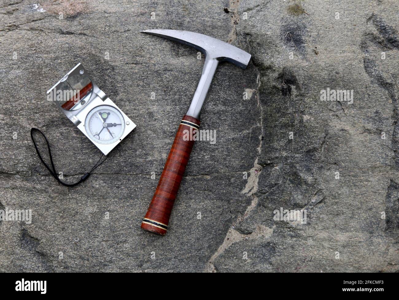 Geologen Kompass auf den Steinen mit Hammer. Konzept der Geologie-Wissenschaft. Der Hammer und die Werkzeuge des Geologen sind auf einem Stein angelegt Stockfoto