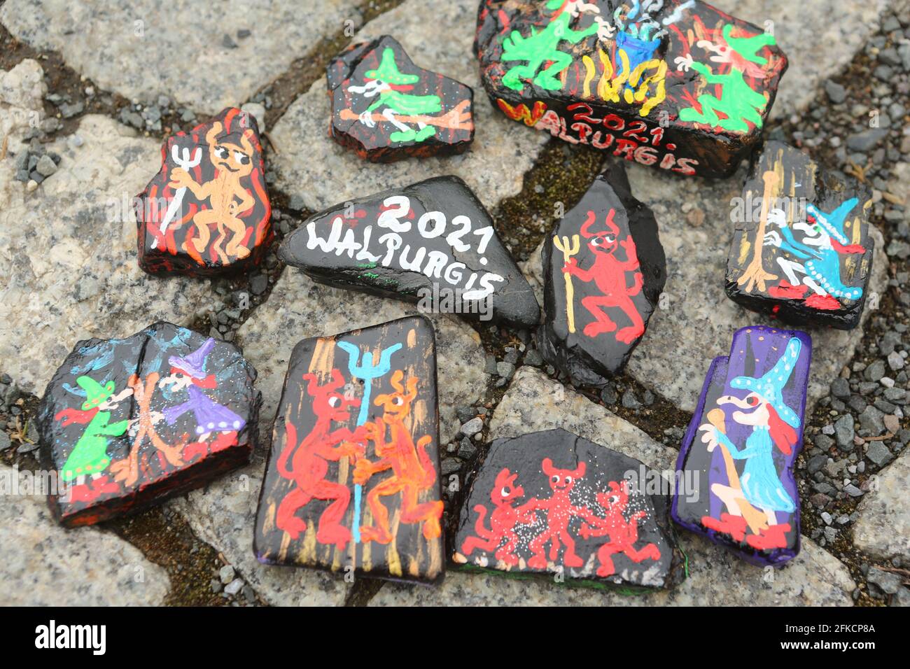 Schierke, Deutschland. April 2021. Auf einem Pfad liegen Harzsteine mit Walpurgismotiven. Die handbemalten Steine sind angelegt und können von Wanderern gefunden und wieder versteckt werden. Ein beliebtes Spiel, das viele Anhänger in sozialen Netzwerken hat. Zum zweiten Mal in Folge werden die Walpurgisfeiern im Harz aufgrund der Corona-Pandemie abgesagt. Im Harz auf Walpurgis werden in der Regel Zehntausende von Besuchern erwartet. Quelle: Matthias Bein/dpa-Zentralbild/dpa/Alamy Live News Stockfoto