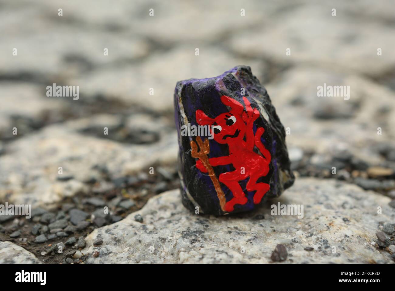 Schierke, Deutschland. April 2021. Ein Harzstein mit Walpurgismotiv liegt auf einem Pfad. Die handbemalten Steine sind angelegt und können von Wanderern gefunden und wieder versteckt werden. Ein beliebtes Spiel, das viele Anhänger in sozialen Netzwerken hat. Zum zweiten Mal in Folge werden die Walpurgisfeiern im Harz aufgrund der Corona-Pandemie abgesagt. Im Harz auf Walpurgis werden in der Regel Zehntausende von Besuchern erwartet. Quelle: Matthias Bein/dpa-Zentralbild/dpa/Alamy Live News Stockfoto