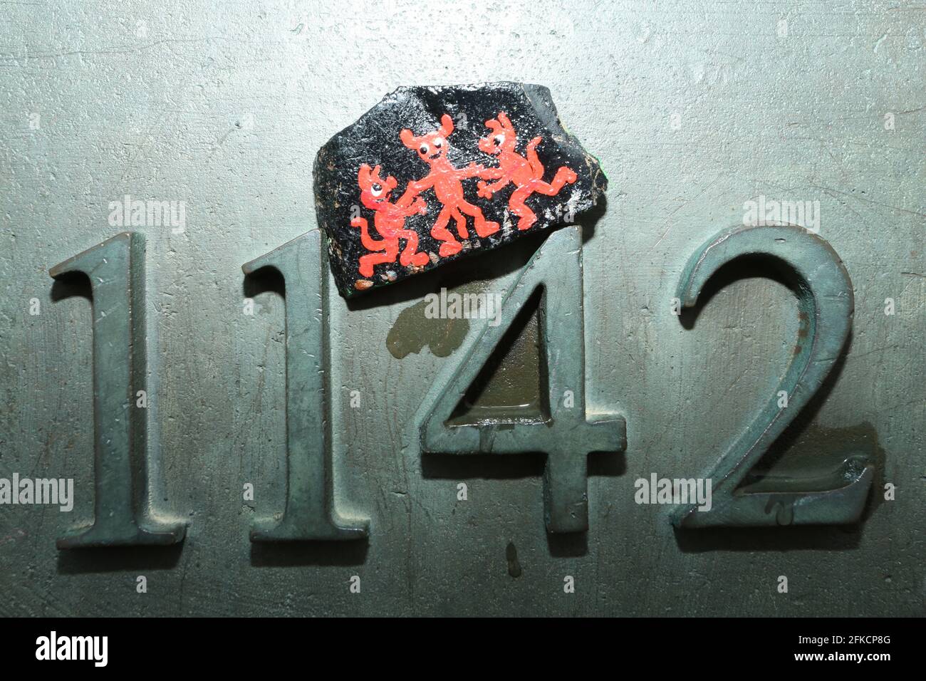 Schierke, Deutschland. April 2021. Auf einem Höhenmarker am Brocken liegt ein Harzstein mit Walpurgis-Motiv. Die handbemalten Steine sind angelegt und können von Wanderern gefunden und wieder versteckt werden. Ein beliebtes Spiel, das viele Anhänger in sozialen Netzwerken hat. Zum zweiten Mal in Folge werden die Walpurgisfeiern im Harz aufgrund der Corona-Pandemie abgesagt. Im Harz auf Walpurgis werden in der Regel Zehntausende von Besuchern erwartet. Quelle: Matthias Bein/dpa-Zentralbild/dpa/Alamy Live News Stockfoto