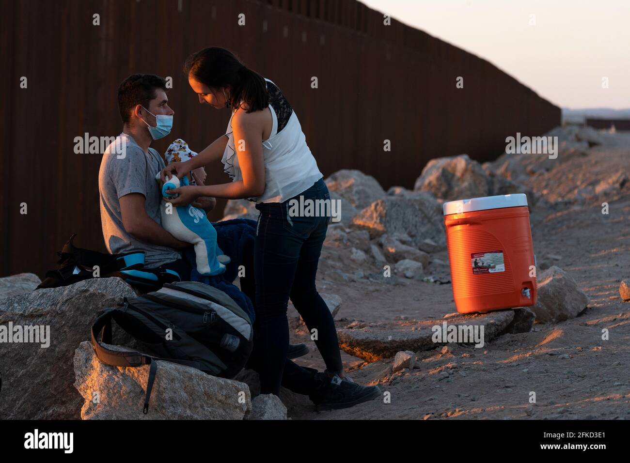 Yuma, Arizona, USA. April 2021. Asylbewerber aus Zentralamerika neigen zu ihrem Kind, während sie von der US-Grenzpolizei an der Grenzmauer nach der Überfahrt in die USA festgehalten werden. Quelle: Cheney Orr/ZUMA Wire/Alamy Live News Stockfoto