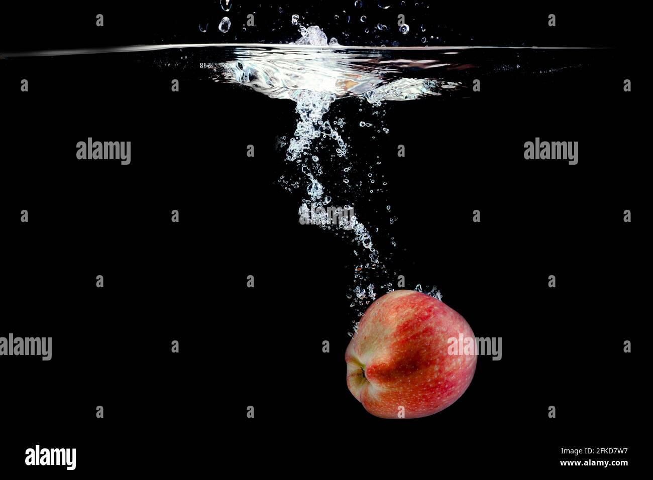Reifer roter Apfel fiel mit Spritzern ins Wasser Stockfoto
