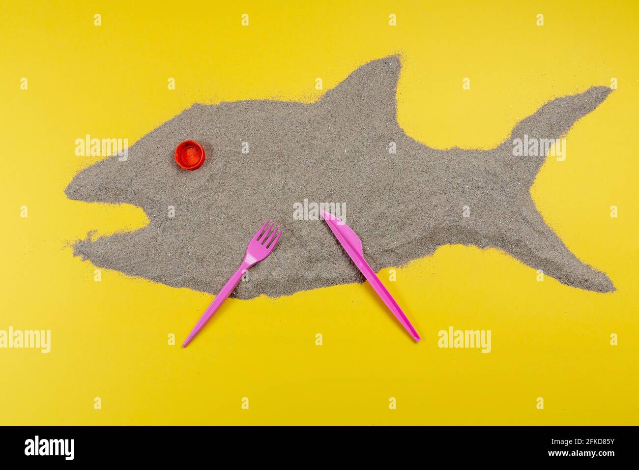 Abendessen aus Fisch aus Sand und Plastikkorken zubereitet. Eine Idee für Werbung. Das Konzept der Ökologie. Stockfoto