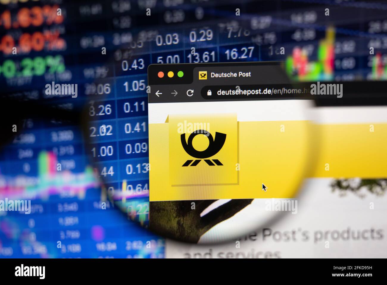 Logo der Deutschen Post auf einer Website mit verschwommenen Börsenentwicklungen im Hintergrund, die auf einem Computerbildschirm durch eine Lupe gesehen werden Stockfoto