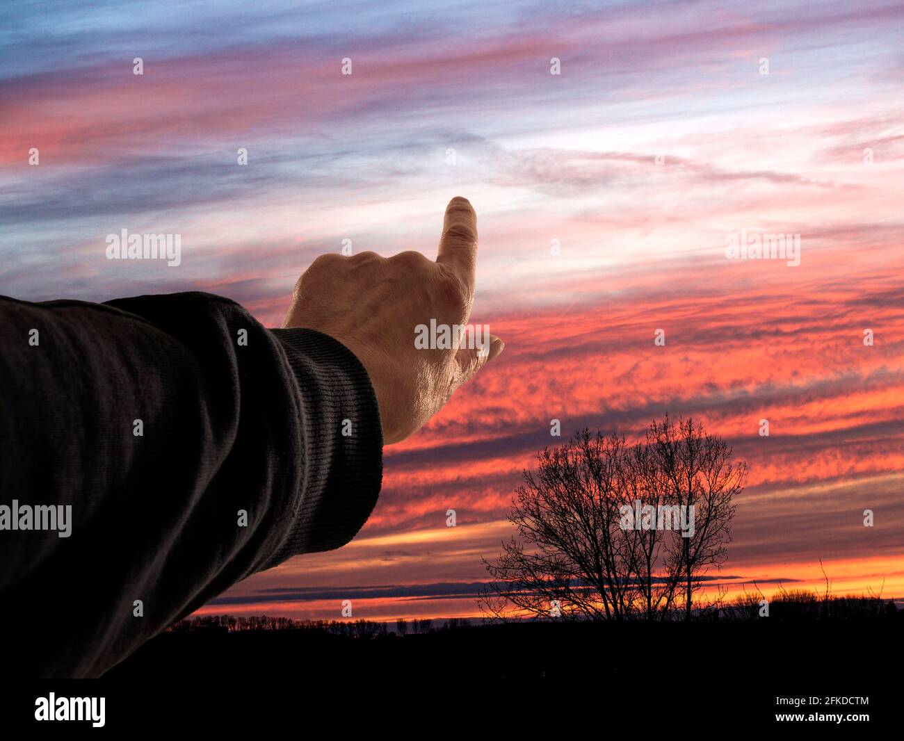 Hand zeigt auf den Sonnenuntergang Stockfoto
