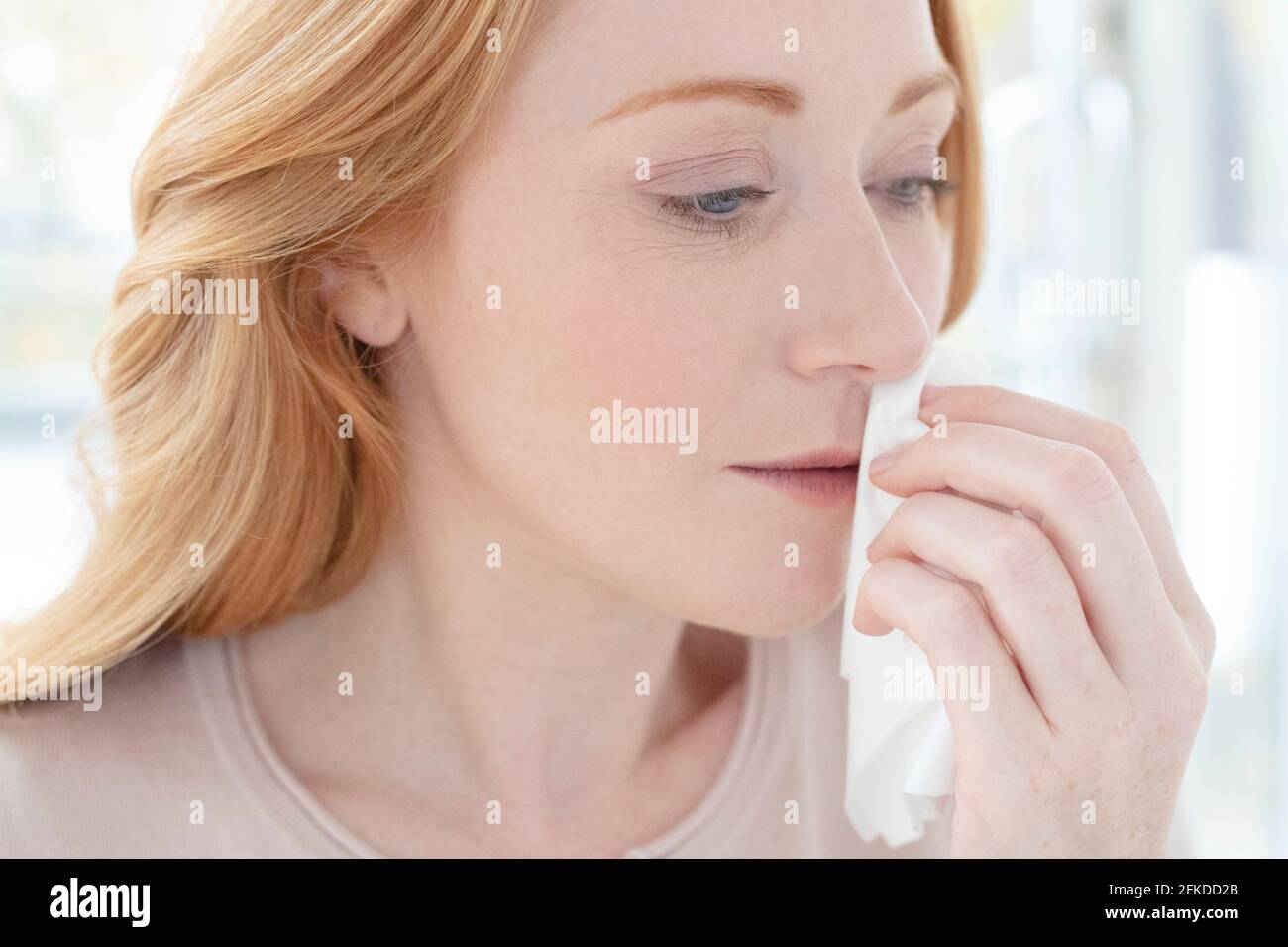 Frau, die ihre Nase abwischen Stockfoto