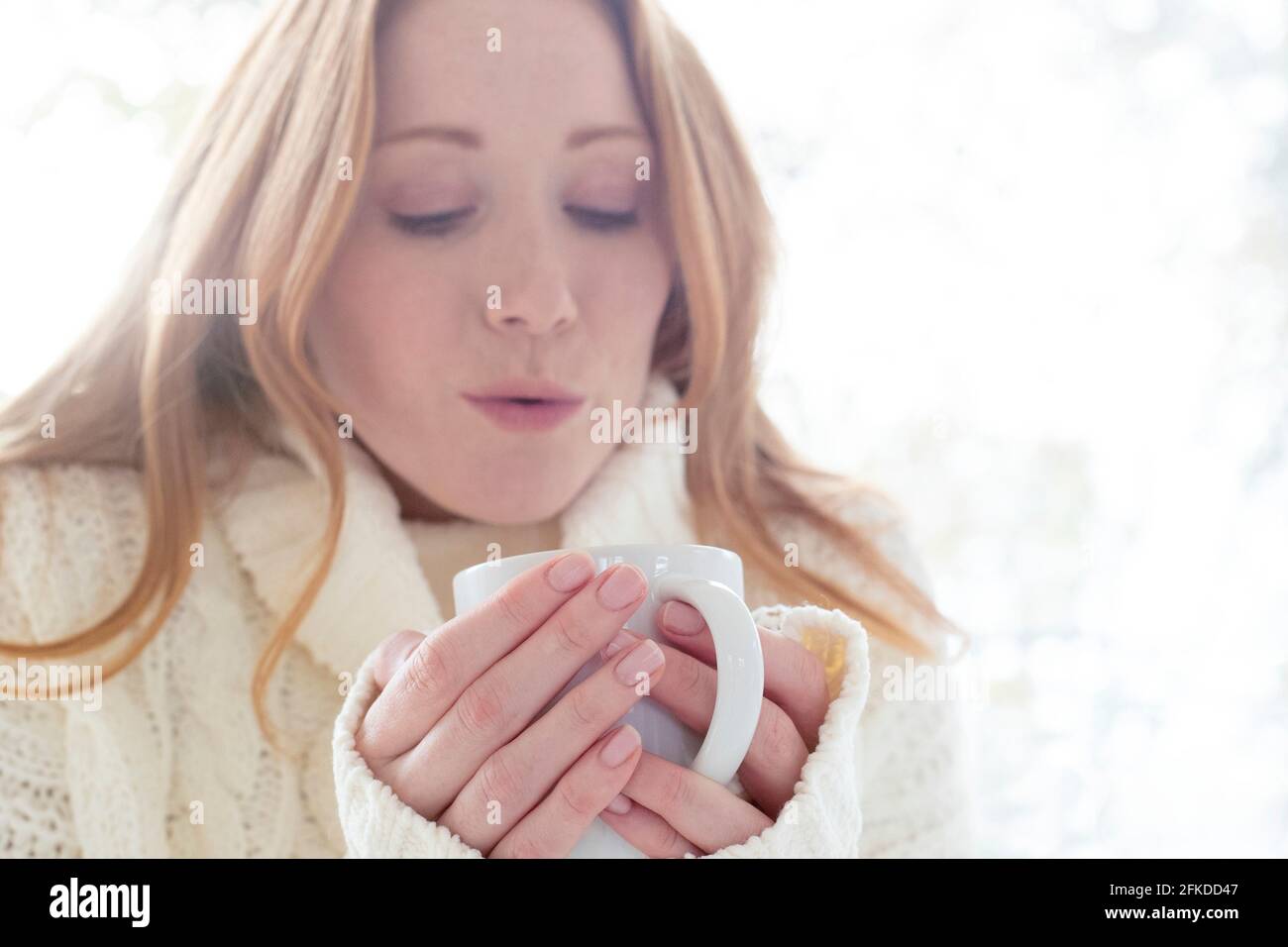 Frau bläst auf heißes Getränk Stockfoto