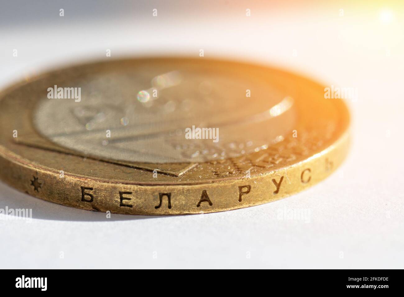 Belarussisches Geld auf weißem Hintergrund mit Lichtreflexen. Weißrussische Münze im Makro in Stückelungen von zwei Rubeln mit der Aufschrift auf dem Seitenrand Stockfoto