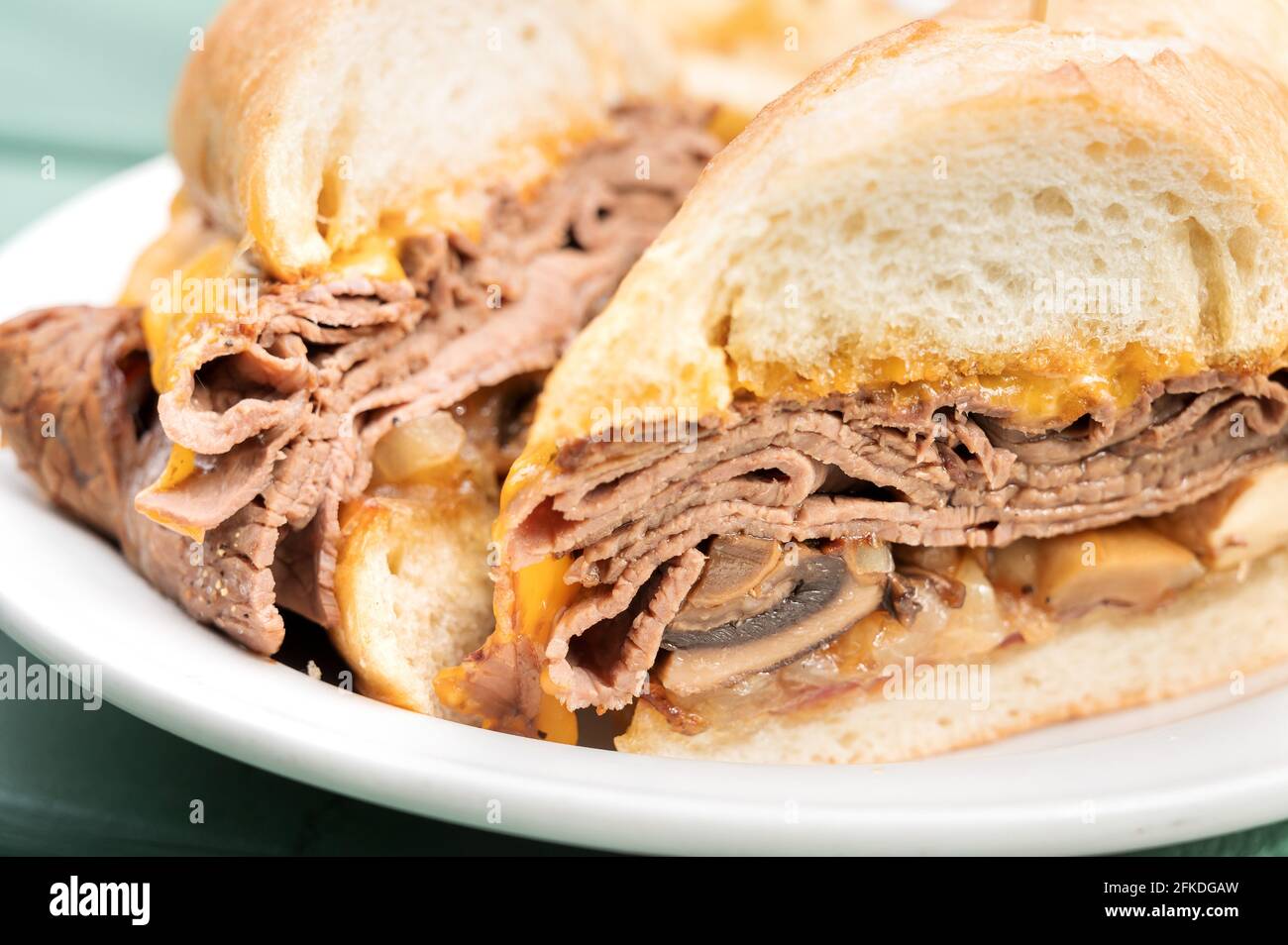 Rindfleisch-Dip-Sandwich, Rasierte Roastbeef, Pilze und Speck auf einem Baguette-Brötchen. Stockfoto