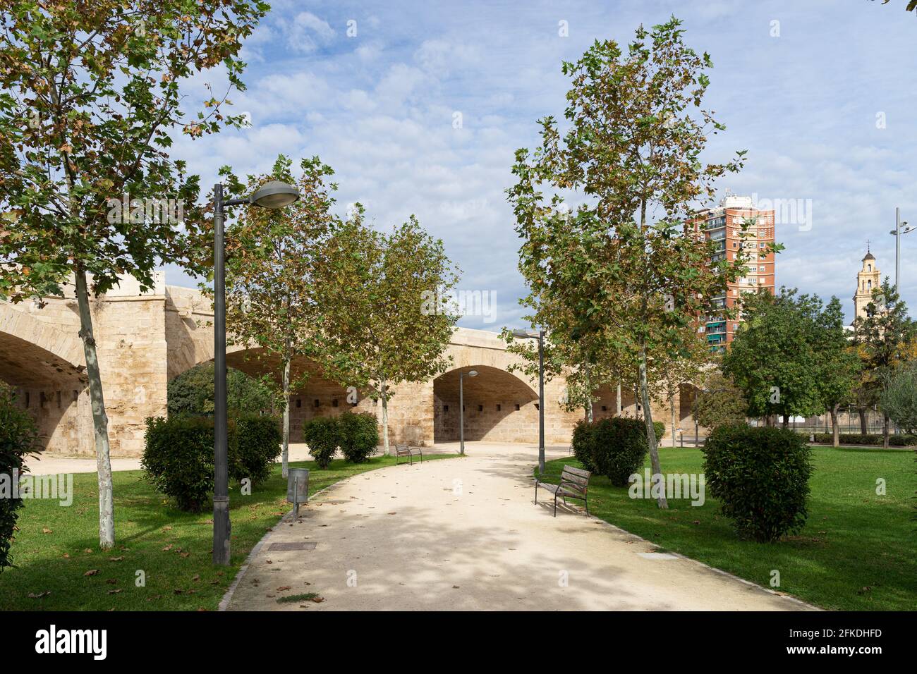 Pfad mit Bank zur alten Steinbrücke über das alte Flussbett. Puente del Real, Fluss Turia, Valencia, Spanien Stockfoto