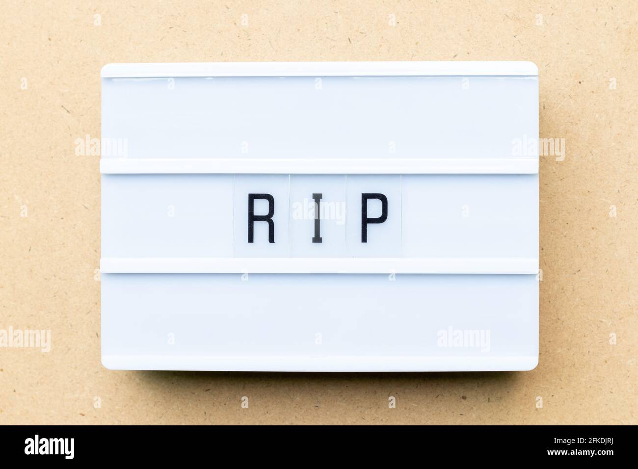 Weißer Leuchtkasten mit dem Wort RIP (Abkürzung für Rest in Peace) Auf Holzhintergrund Stockfoto