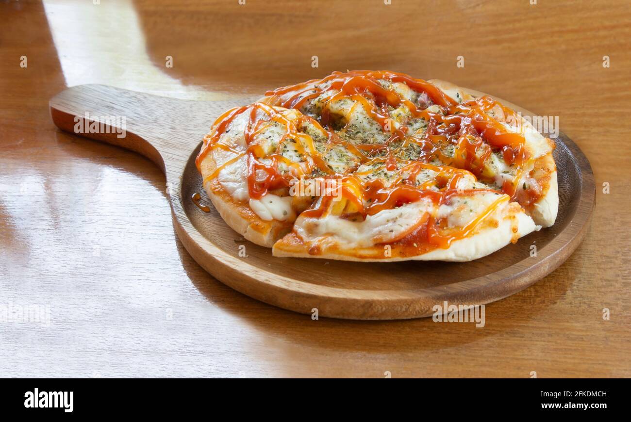 Mini-Pizza auf Holzplatte voll und lecker für eine Person. Stockfoto