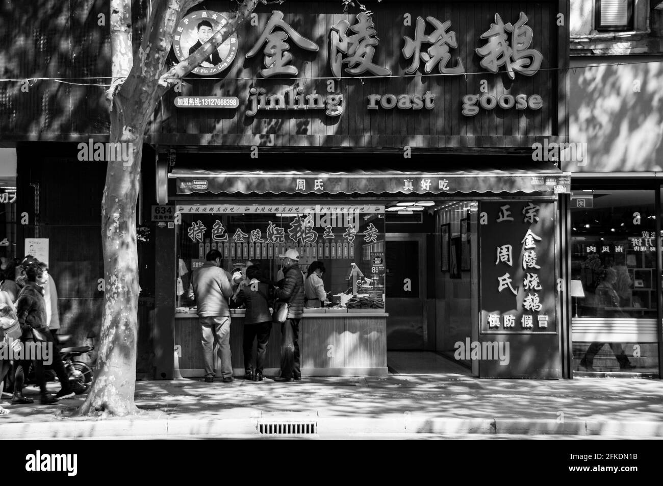 Menschen, die im Jinling Roast Goose-Laden am Huai Hai Zhong lu im Zentrum von Shanghai, China, eine gebratene Gans kaufen. Stockfoto