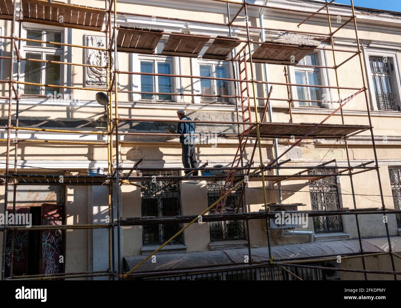 Man Baumeister ohne Bauhelm arbeiten in unsicherer Weise von Gerüsten, um historische Gebäude zu renovieren. Historische Gebäudesanierung in Progres Stockfoto