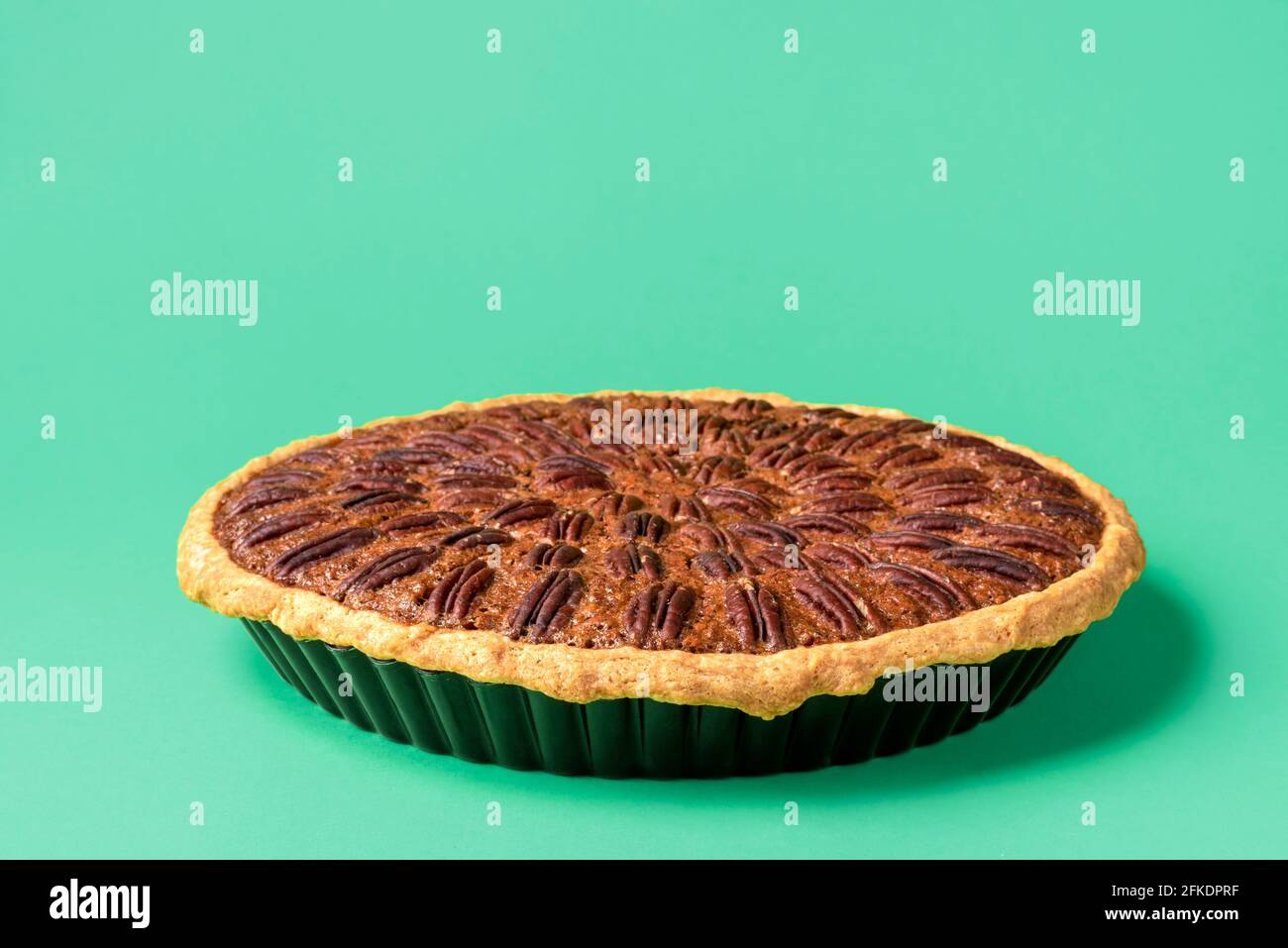 Nahaufnahme mit einer frisch gebackenen Pekannüsse auf grünem Hintergrund. Hausgemachter Kuchen mit Pekannüssen und Maissirup. Stockfoto