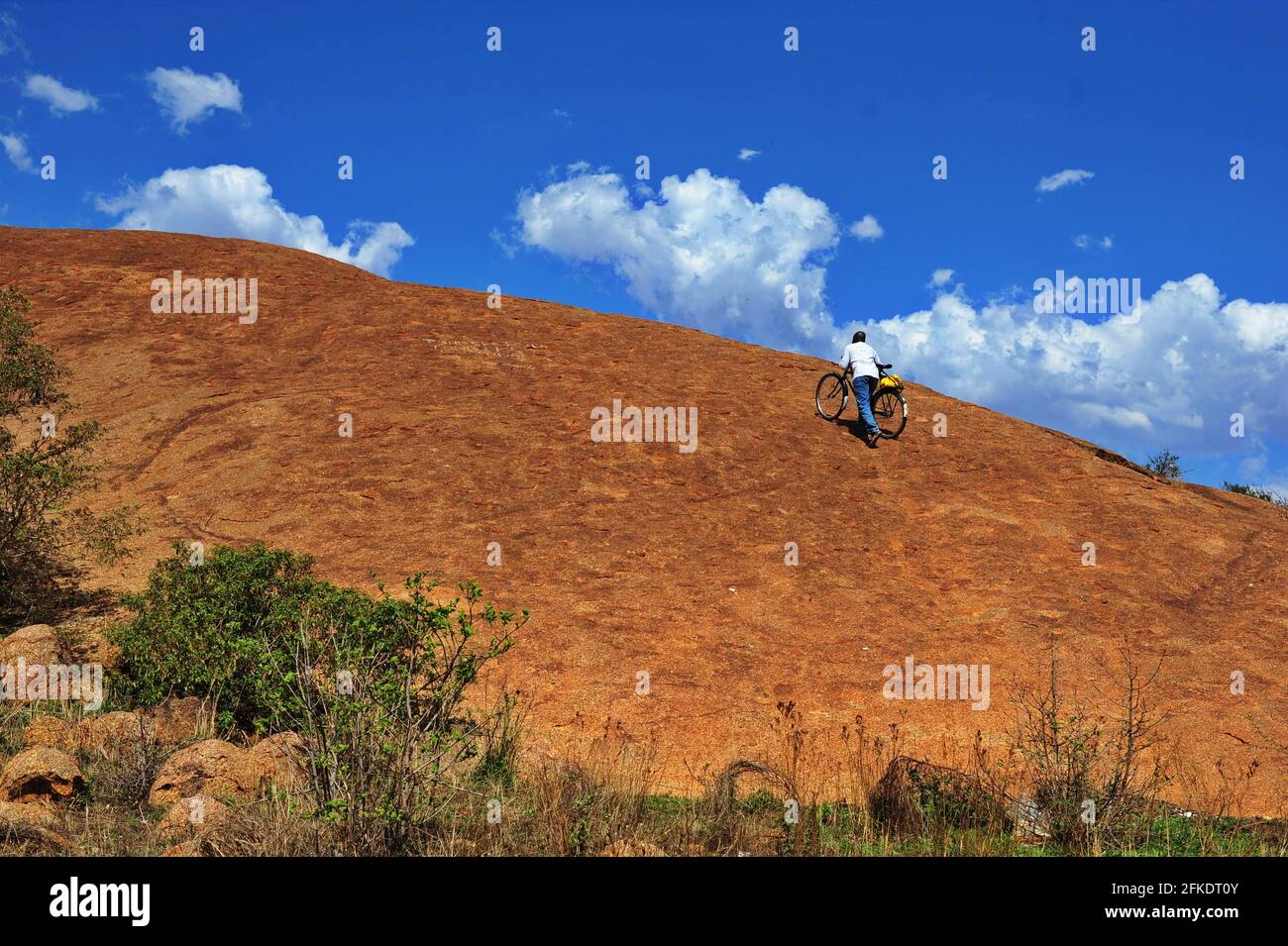 Afrikanische Gläubige, die in Limpopo, Südafrika, einen felsigen Hügel hinaufgehen, um an einem klaren Tag mit blauem Himmel zu beten Stockfoto